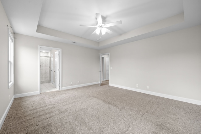 spare room featuring light colored carpet, a raised ceiling, and ceiling fan