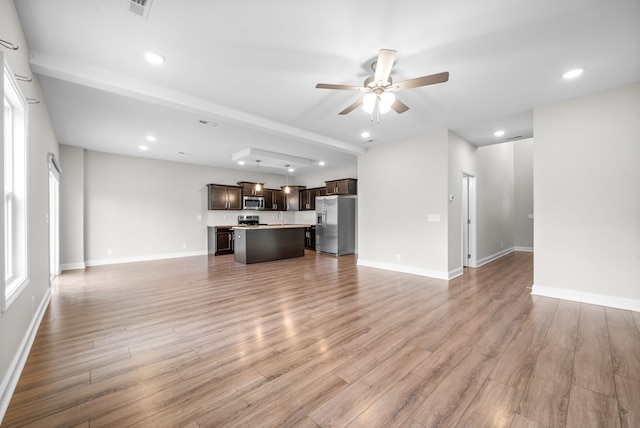 unfurnished living room featuring hardwood / wood-style floors, ceiling fan, and beam ceiling