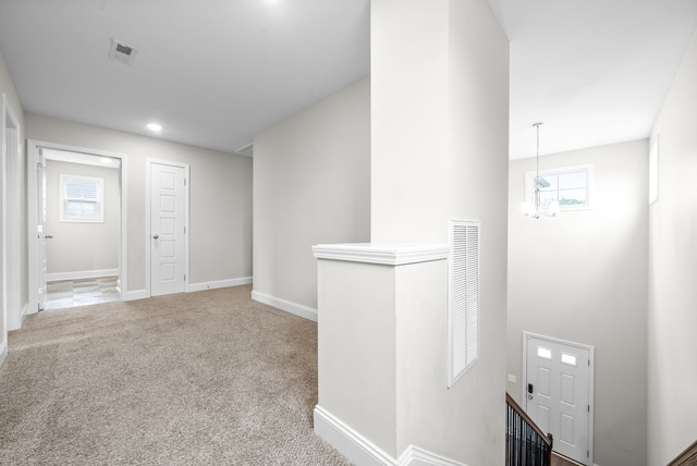 hallway with carpet floors and a notable chandelier