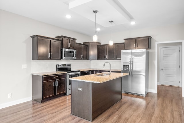 kitchen with dark brown cabinetry, sink, stainless steel appliances, light stone counters, and pendant lighting