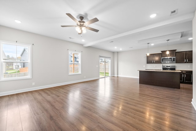 unfurnished living room featuring beamed ceiling, ceiling fan, and dark hardwood / wood-style flooring