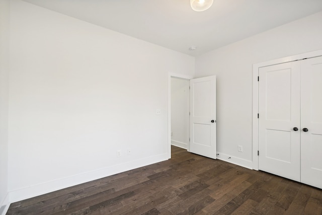 unfurnished bedroom with dark hardwood / wood-style flooring and a closet