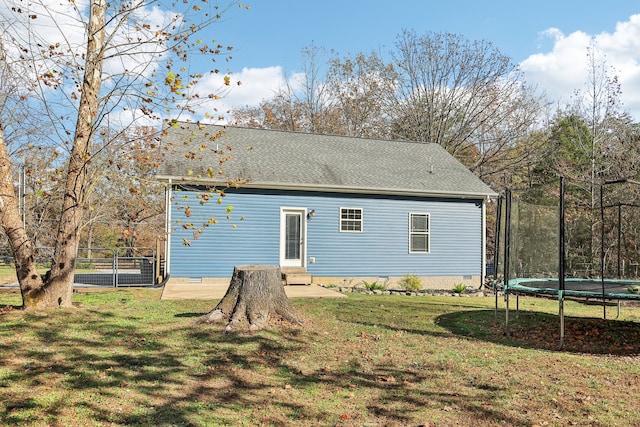 rear view of house featuring a yard and a trampoline