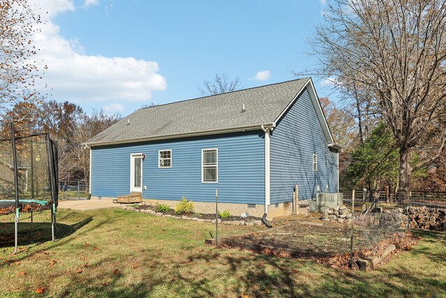 back of property with a yard, a trampoline, and a patio