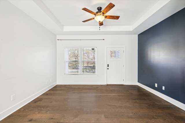 spare room featuring a raised ceiling, ceiling fan, and dark hardwood / wood-style flooring