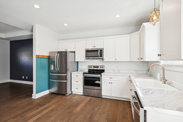 kitchen featuring dark wood-type flooring, white cabinets, stainless steel appliances, and decorative light fixtures