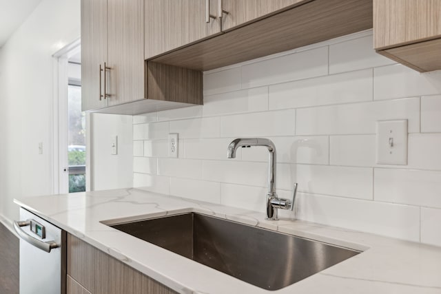 kitchen with backsplash, light stone counters, sink, light brown cabinets, and dishwasher