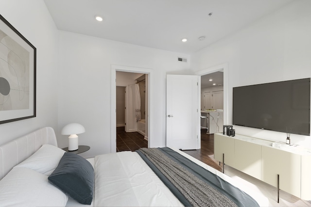 bedroom featuring ensuite bathroom and dark hardwood / wood-style flooring