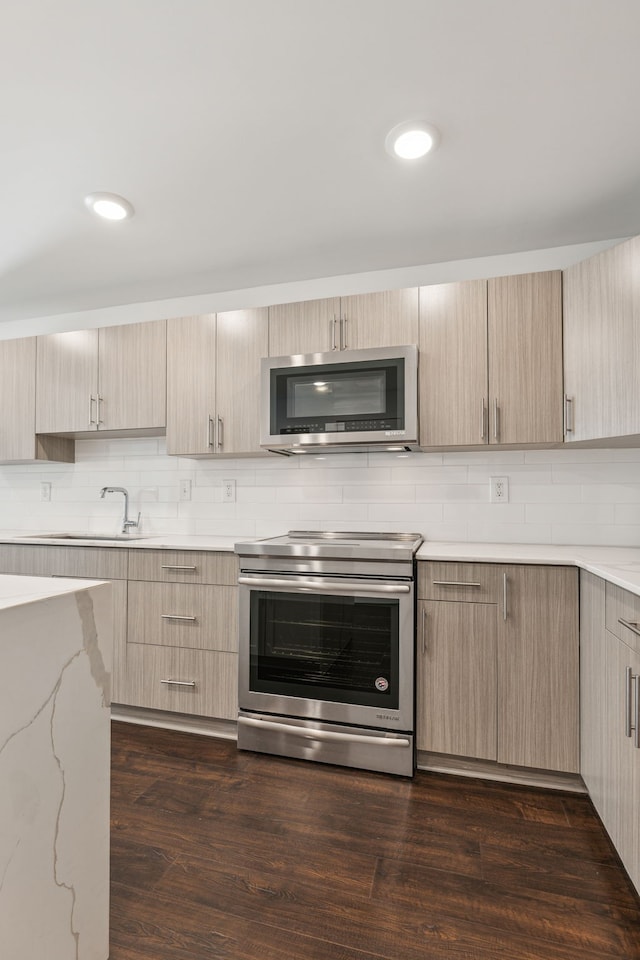 kitchen with appliances with stainless steel finishes, light brown cabinets, and dark wood-type flooring