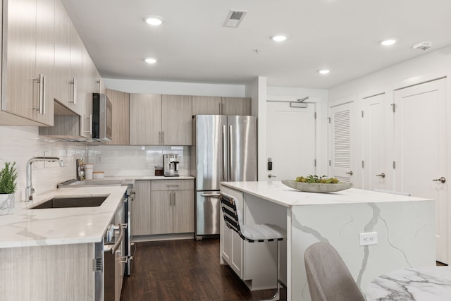 kitchen featuring sink, light stone countertops, appliances with stainless steel finishes, dark hardwood / wood-style flooring, and a breakfast bar area