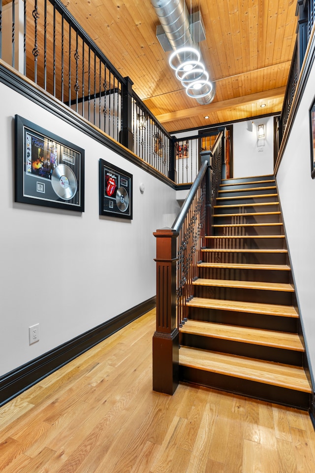 staircase with hardwood / wood-style flooring, wood ceiling, and an inviting chandelier