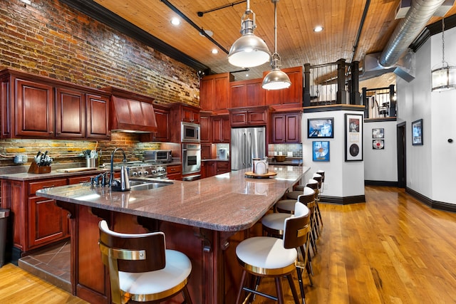 kitchen featuring a kitchen island with sink, hardwood / wood-style floors, stainless steel appliances, and sink