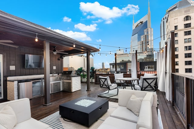 wooden terrace with area for grilling, ceiling fan, an outdoor living space with a fire pit, and an outdoor kitchen