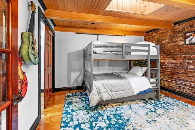 bedroom with a skylight, brick wall, light hardwood / wood-style flooring, wooden ceiling, and beamed ceiling