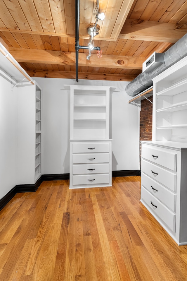 spacious closet featuring beamed ceiling and light hardwood / wood-style floors