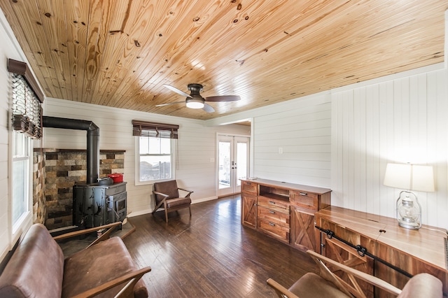 sitting room featuring french doors, dark hardwood / wood-style flooring, wooden walls, wooden ceiling, and a wood stove