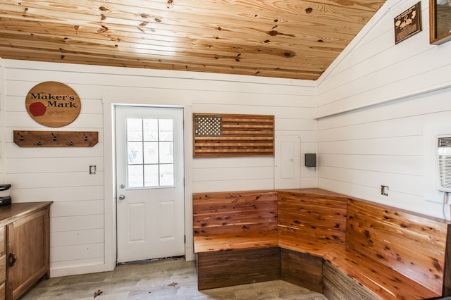 interior space featuring light wood-type flooring, vaulted ceiling, wooden walls, and wood ceiling