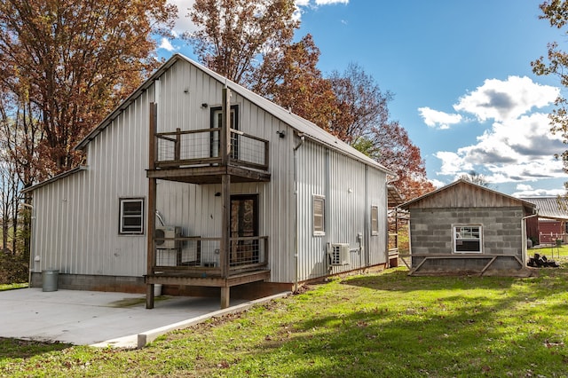 rear view of property featuring a lawn, a balcony, central air condition unit, and a patio