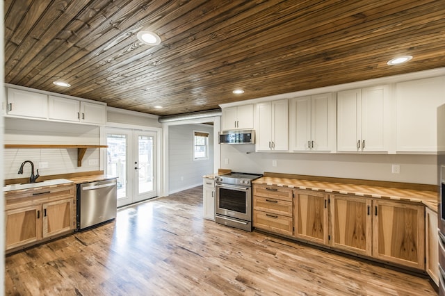 kitchen with butcher block counters, white cabinetry, french doors, sink, and stainless steel appliances