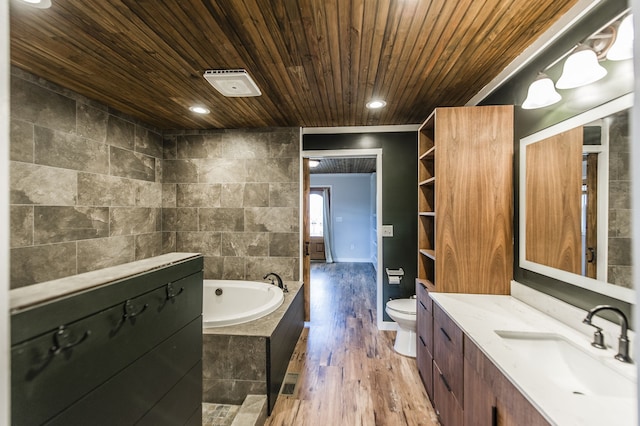 bathroom with vanity, toilet, tile walls, wood-type flooring, and tiled bath