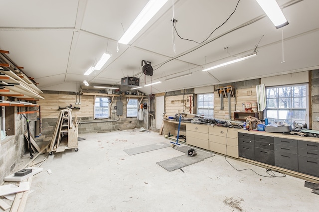 misc room featuring a workshop area, concrete flooring, electric panel, and vaulted ceiling