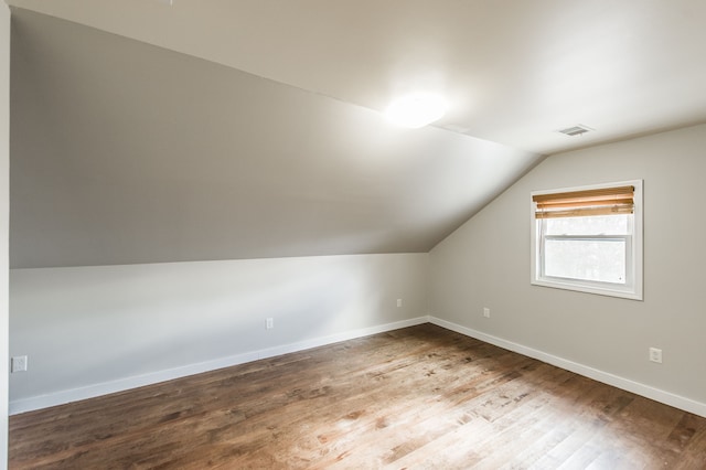 additional living space with hardwood / wood-style floors and vaulted ceiling