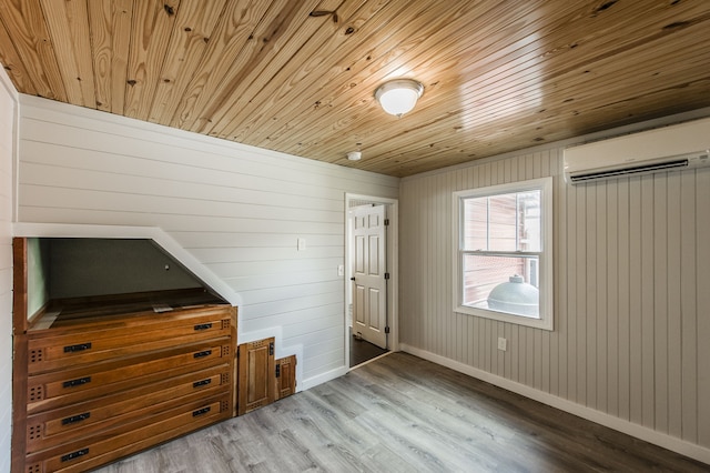 unfurnished bedroom featuring light hardwood / wood-style flooring, wood walls, and a wall unit AC