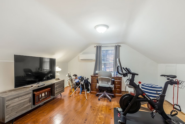 exercise area with a wall unit AC, light hardwood / wood-style flooring, and vaulted ceiling