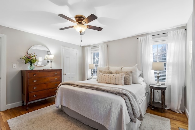 bedroom featuring wood-type flooring, multiple windows, and ceiling fan