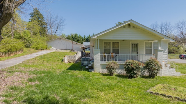 bungalow-style home featuring an outdoor structure, a garage, a porch, and a front yard