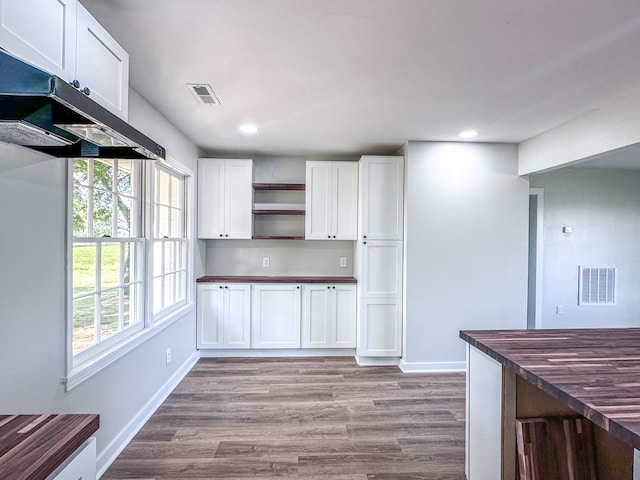 kitchen with white cabinets, light wood-type flooring, range hood, and wooden counters