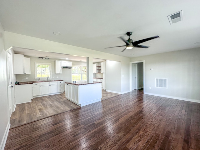 kitchen with white cabinets, a kitchen island, ceiling fan, and dark wood-type flooring