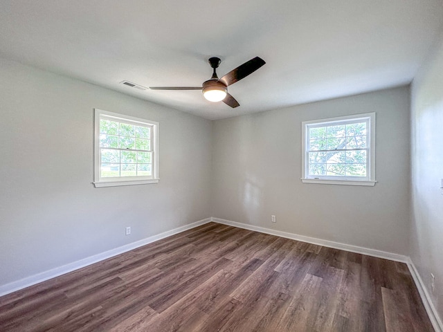 spare room with a wealth of natural light, ceiling fan, and dark wood-type flooring