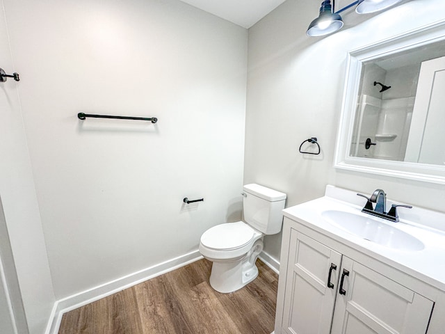 bathroom with hardwood / wood-style floors, vanity, toilet, and walk in shower