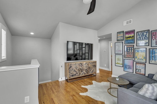 living room with ceiling fan, light hardwood / wood-style floors, and lofted ceiling