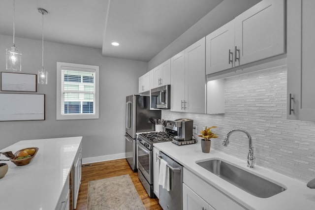 kitchen featuring sink, tasteful backsplash, decorative light fixtures, white cabinets, and appliances with stainless steel finishes