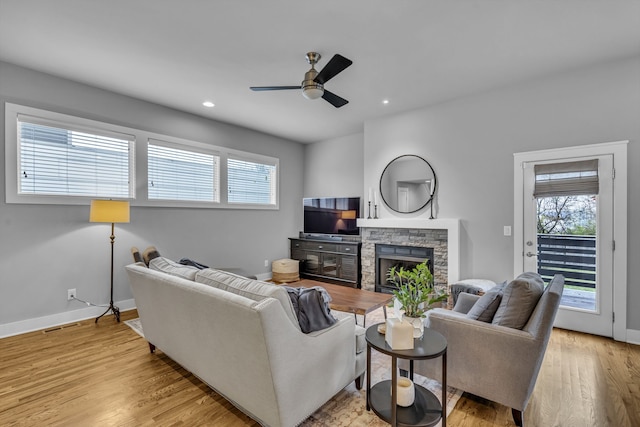 living room with a fireplace, ceiling fan, and light hardwood / wood-style flooring