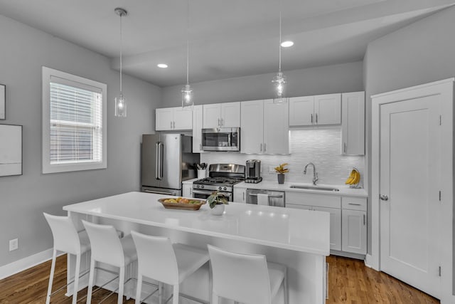 kitchen with appliances with stainless steel finishes, white cabinetry, a breakfast bar area, and sink