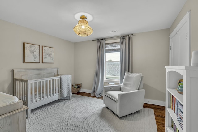 bedroom with hardwood / wood-style flooring and a crib