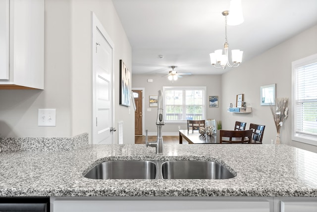 kitchen featuring white cabinetry, hanging light fixtures, and light stone counters