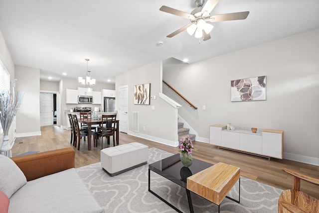 living room with light hardwood / wood-style flooring and ceiling fan with notable chandelier