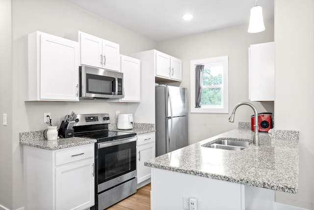 kitchen featuring sink, hanging light fixtures, white cabinetry, kitchen peninsula, and stainless steel appliances