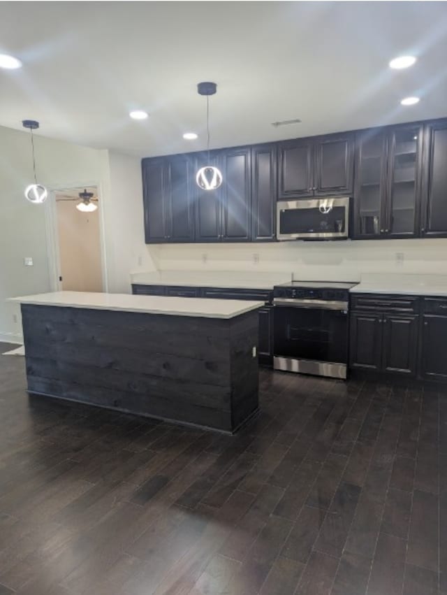 kitchen featuring appliances with stainless steel finishes, hanging light fixtures, dark wood-type flooring, and ceiling fan