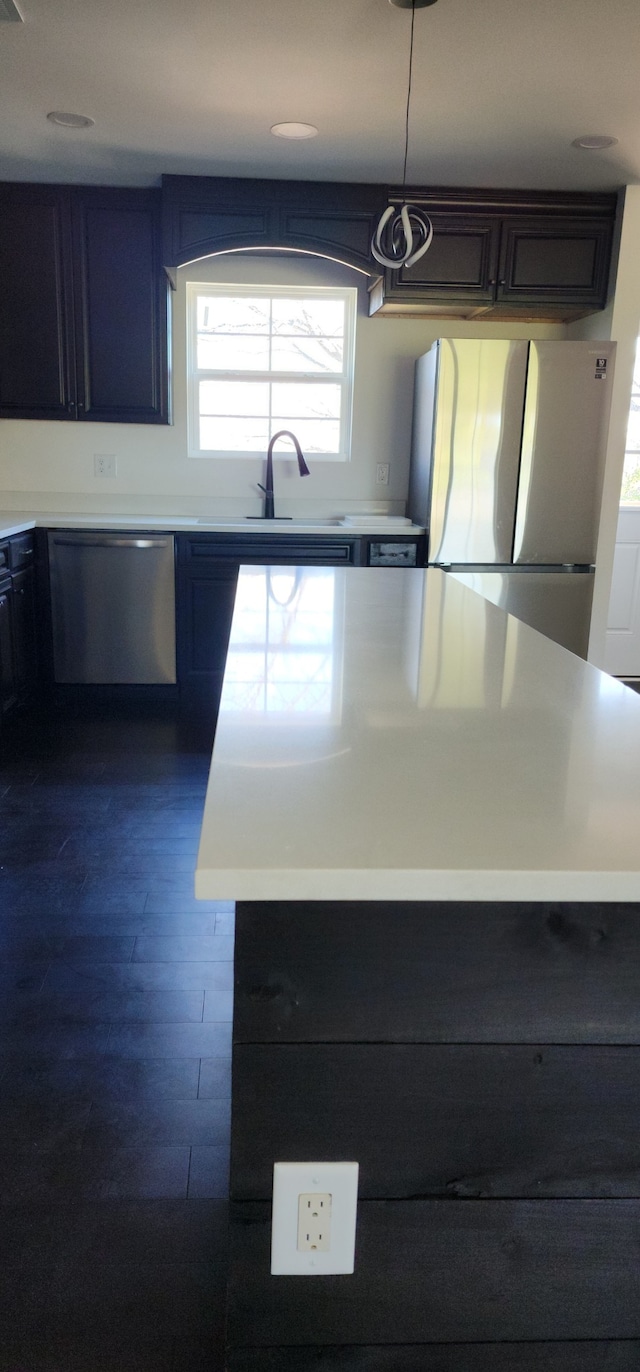 kitchen with appliances with stainless steel finishes, dark hardwood / wood-style flooring, hanging light fixtures, and sink