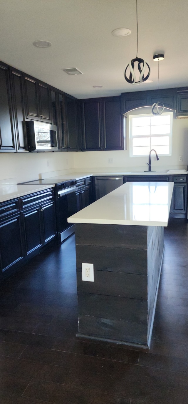 kitchen with sink, a kitchen island, hanging light fixtures, and dark hardwood / wood-style floors