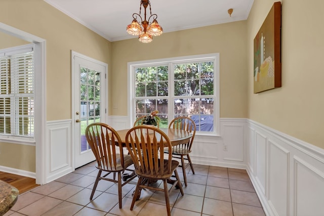 tiled dining space featuring crown molding and an inviting chandelier