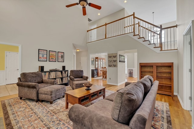 living room featuring hardwood / wood-style flooring, ceiling fan, and a high ceiling