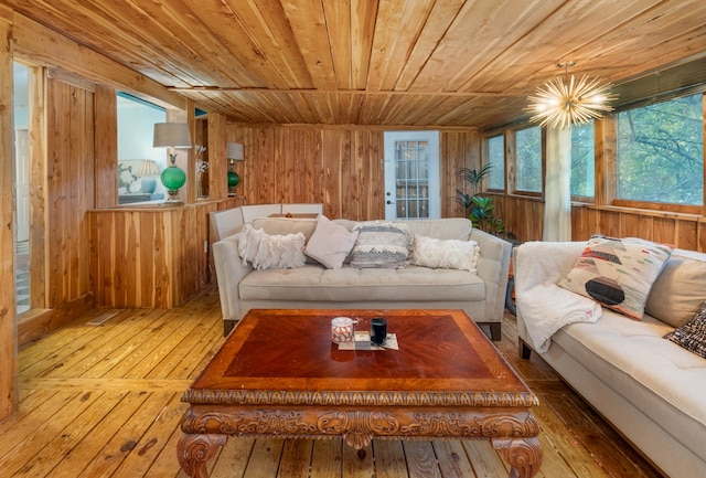 living room with wood ceiling, a notable chandelier, wood-type flooring, and wooden walls