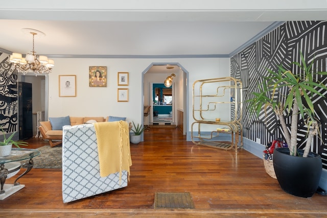 living room with crown molding, dark hardwood / wood-style floors, and an inviting chandelier