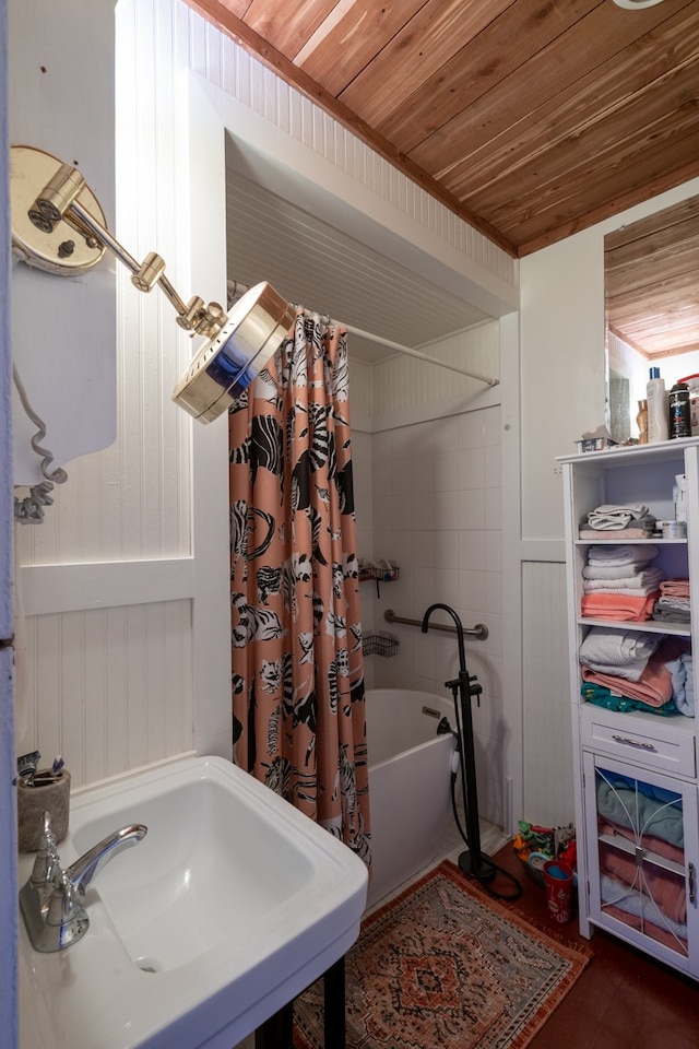 bathroom featuring wooden walls, shower / tub combo with curtain, wooden ceiling, and sink